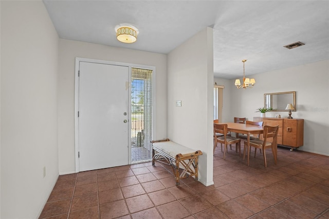 foyer featuring baseboards, dark tile patterned flooring, visible vents, and a notable chandelier