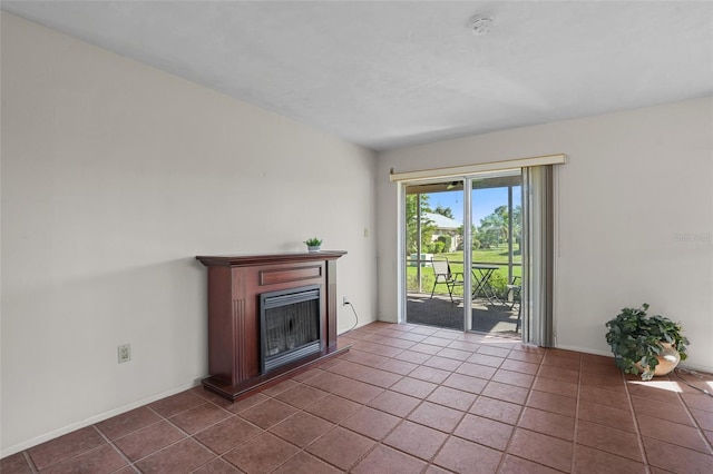 unfurnished living room featuring a fireplace, dark tile patterned floors, and baseboards