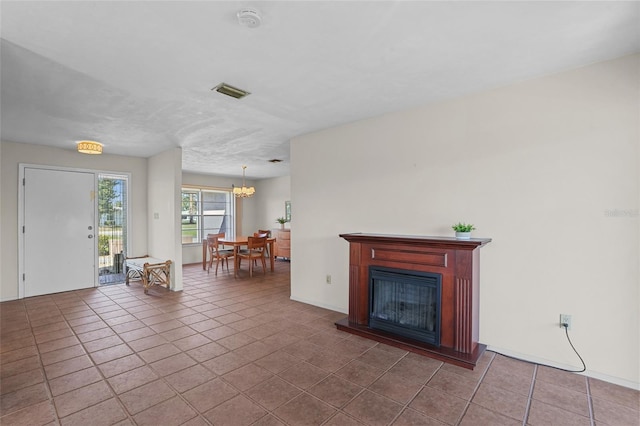 tiled living area with a glass covered fireplace, visible vents, and a notable chandelier