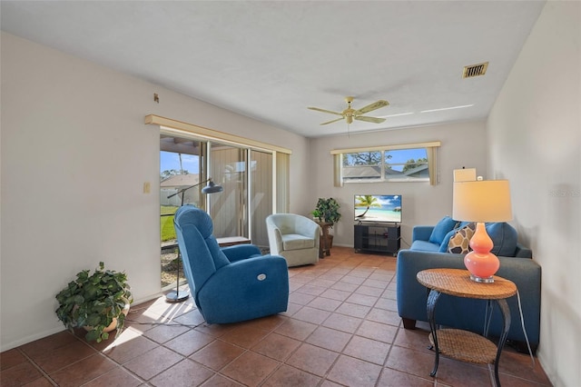 living area with ceiling fan, tile patterned flooring, visible vents, and baseboards