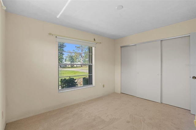 unfurnished bedroom with a closet and light colored carpet