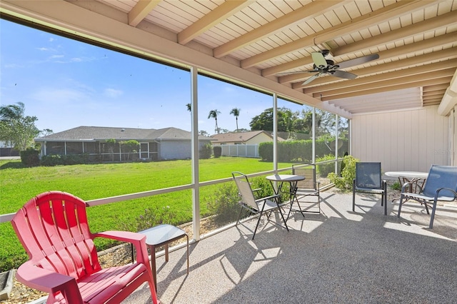 sunroom / solarium featuring ceiling fan and beamed ceiling