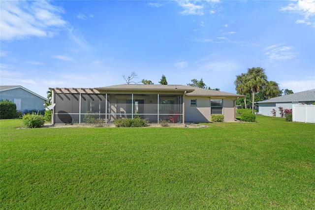 back of house featuring a sunroom, stucco siding, and a yard