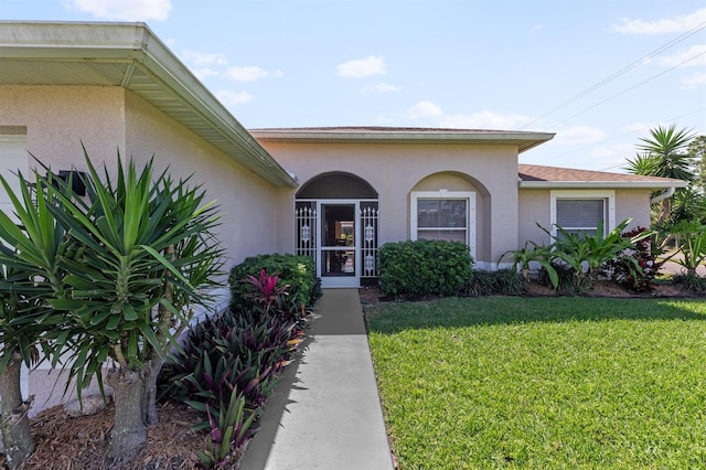 entrance to property featuring a yard and stucco siding