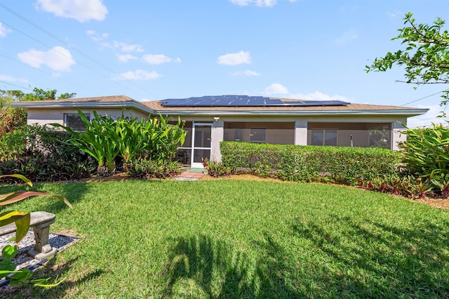 view of front of property featuring solar panels, a front yard, a sunroom, and stucco siding