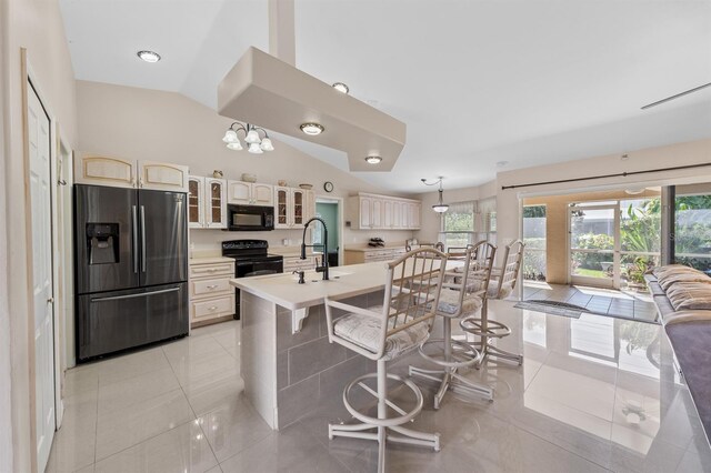 kitchen featuring glass insert cabinets, a breakfast bar area, light countertops, black appliances, and light tile patterned flooring