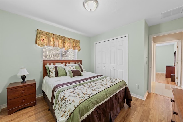 bedroom featuring a closet, visible vents, baseboards, and light wood finished floors