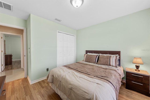 bedroom with baseboards, a closet, visible vents, and light wood-style floors