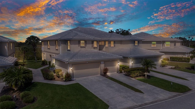 view of front of home featuring a tile roof, a yard, concrete driveway, and stucco siding