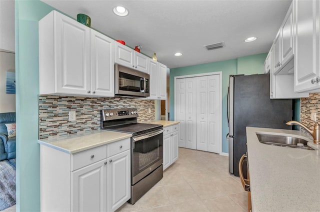 kitchen featuring visible vents, light tile patterned flooring, white cabinets, stainless steel appliances, and a sink