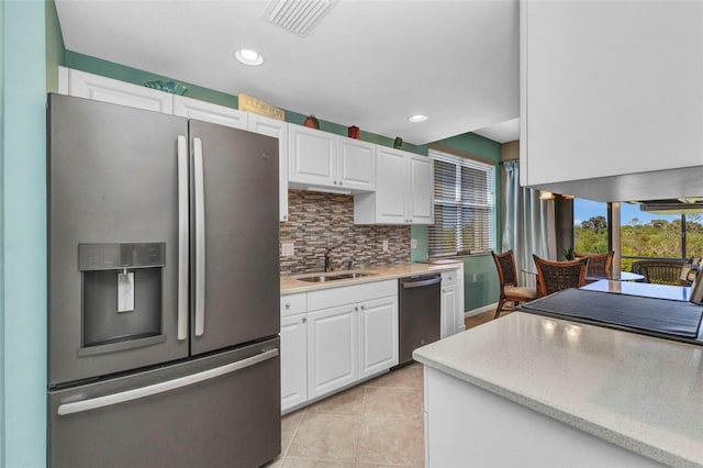 kitchen featuring white cabinets, light tile patterned floors, appliances with stainless steel finishes, and a sink