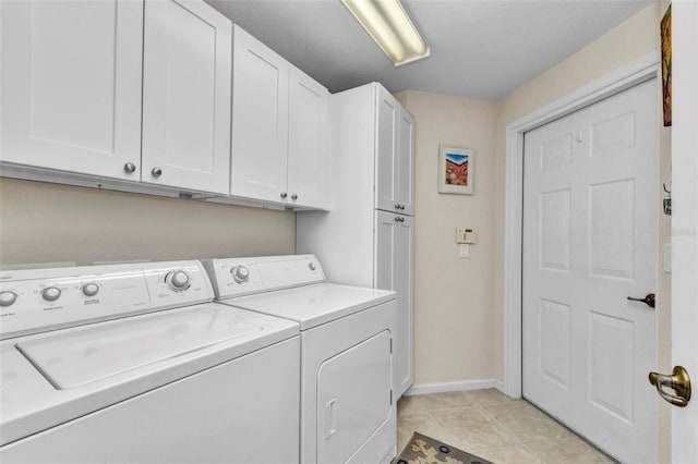 laundry area with washer and dryer, light tile patterned floors, cabinet space, and baseboards