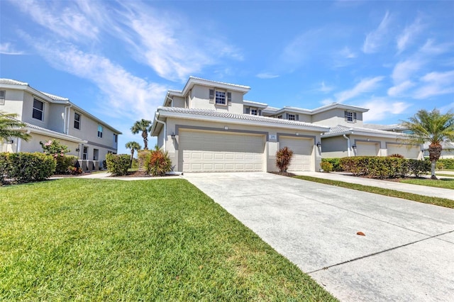 view of front of home with stucco siding, driveway, a tile roof, and a front yard