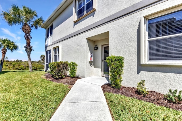 property entrance with stucco siding and a lawn