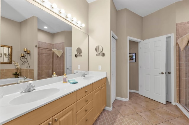 bathroom featuring tile patterned flooring, double vanity, tiled shower, and a sink