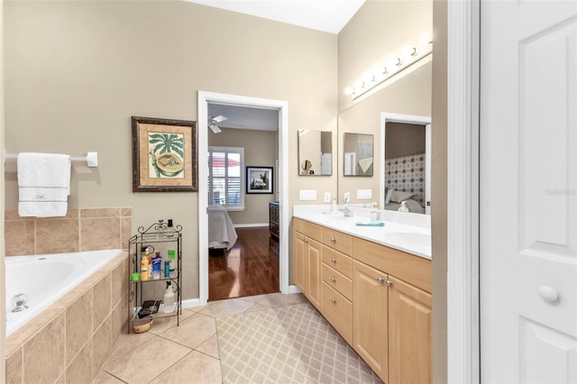 bathroom featuring a garden tub, double vanity, ensuite bathroom, tile patterned floors, and a sink