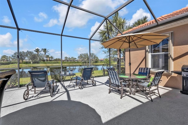 view of patio with a lanai, outdoor dining space, and a water view