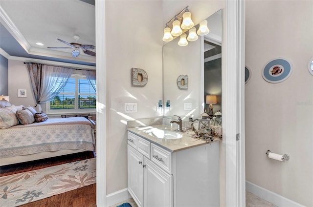 bathroom with a tray ceiling, ensuite bath, crown molding, ceiling fan, and vanity