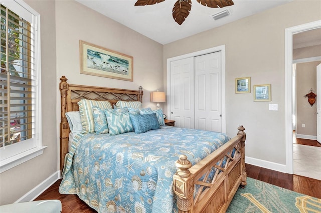 bedroom with wood finished floors, visible vents, a closet, and baseboards