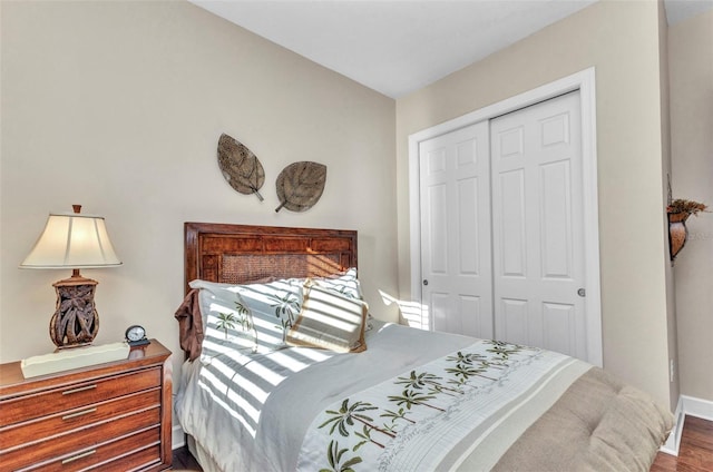 bedroom with wood finished floors, baseboards, and a closet