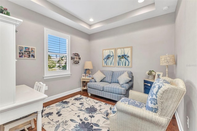 living room featuring recessed lighting, a raised ceiling, baseboards, and wood finished floors