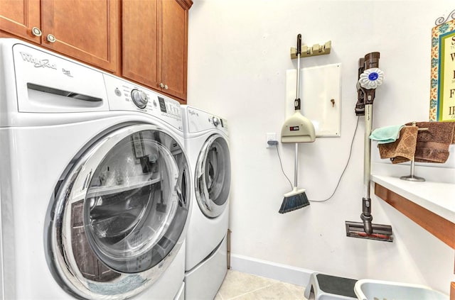 clothes washing area with cabinet space, light tile patterned floors, washing machine and dryer, and baseboards