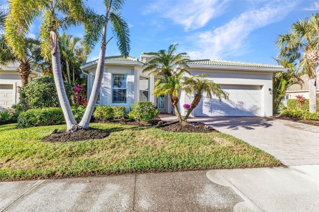 view of front of property with a front lawn, decorative driveway, an attached garage, and stucco siding