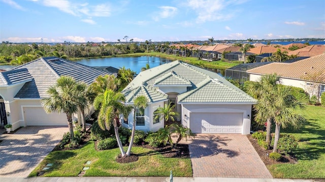 view of front of house with stucco siding, a garage, a water view, a tile roof, and decorative driveway