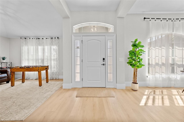 entrance foyer featuring beam ceiling, baseboards, and wood finished floors