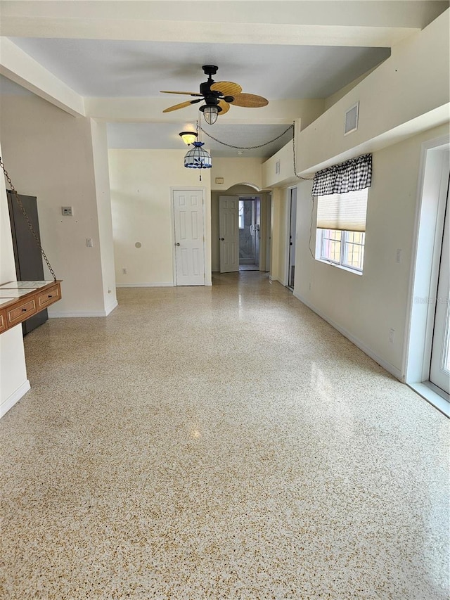 unfurnished living room with arched walkways, visible vents, baseboards, and speckled floor