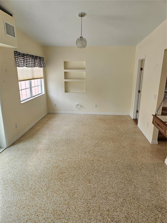 spare room with baseboards, visible vents, and built in features