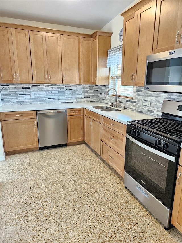 kitchen with light countertops, appliances with stainless steel finishes, a sink, and tasteful backsplash