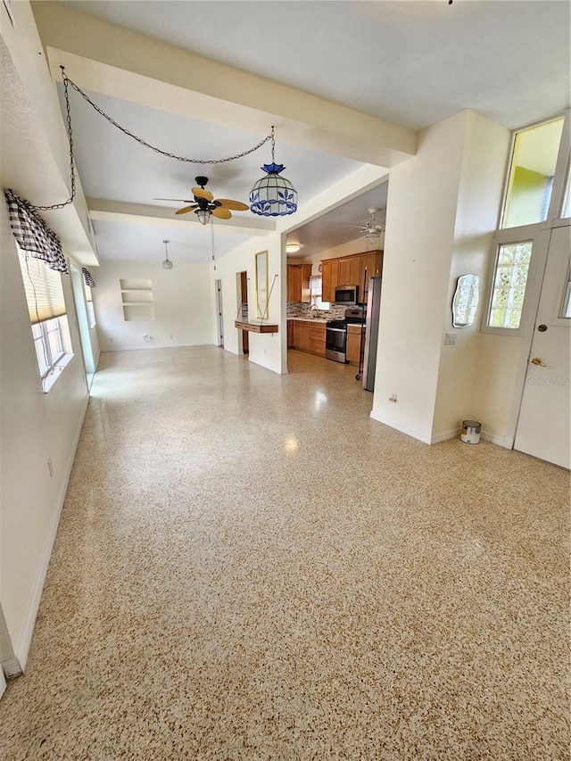 unfurnished living room featuring light speckled floor, ceiling fan, and baseboards