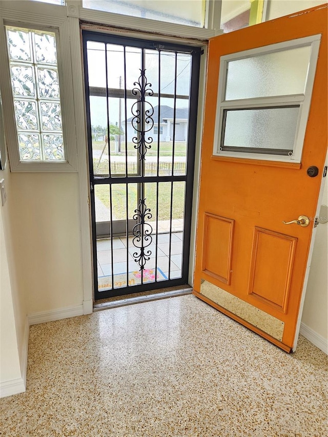 doorway featuring baseboards and speckled floor