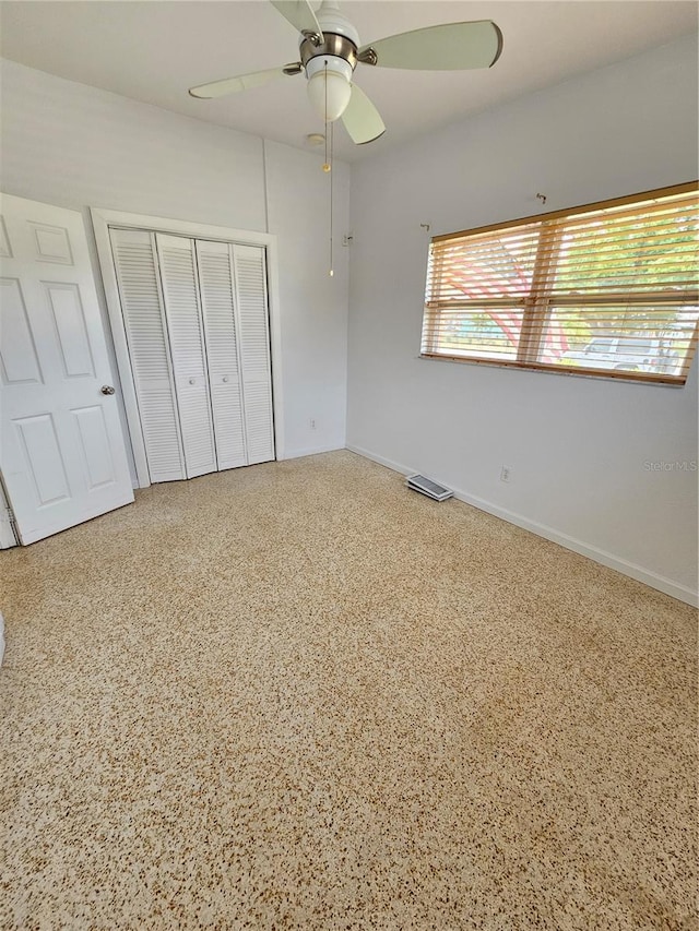 unfurnished bedroom with ceiling fan, speckled floor, a closet, and baseboards