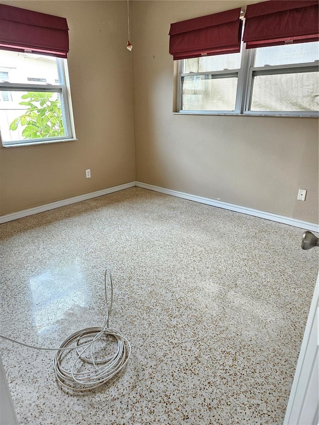 unfurnished room featuring baseboards and speckled floor