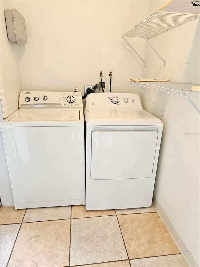 laundry room featuring laundry area, light tile patterned floors, baseboards, and washer and clothes dryer