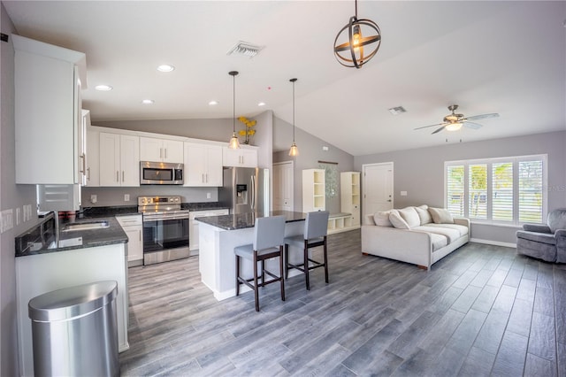 kitchen with stainless steel appliances, a breakfast bar, a kitchen island, visible vents, and open floor plan