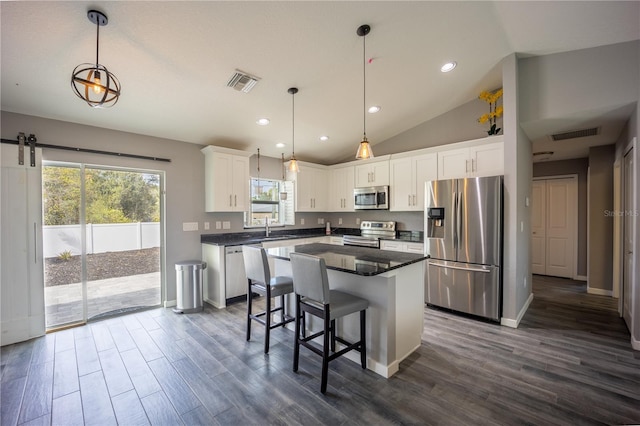 kitchen with stainless steel appliances, dark countertops, visible vents, and a sink