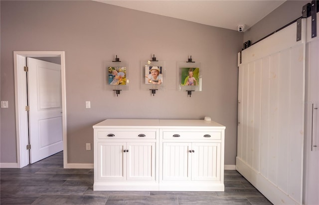 interior space featuring dark wood-style floors, a barn door, and baseboards