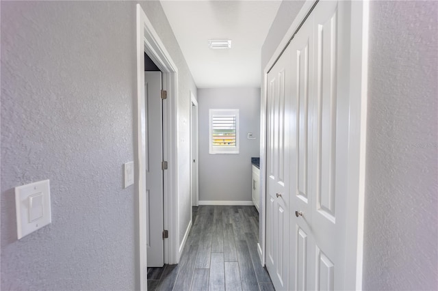 hall with visible vents, baseboards, dark wood finished floors, and a textured wall