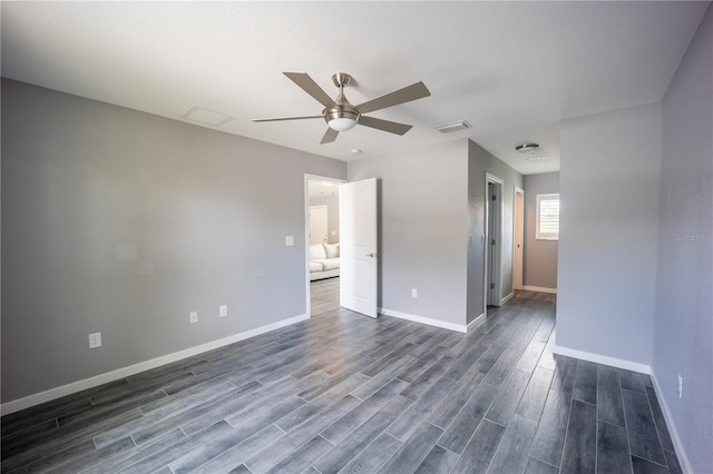 spare room with dark wood-style floors, visible vents, baseboards, and a ceiling fan