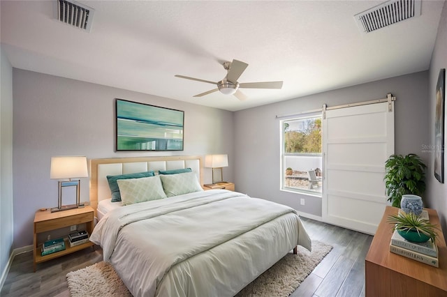 bedroom with a ceiling fan, visible vents, baseboards, and wood finished floors