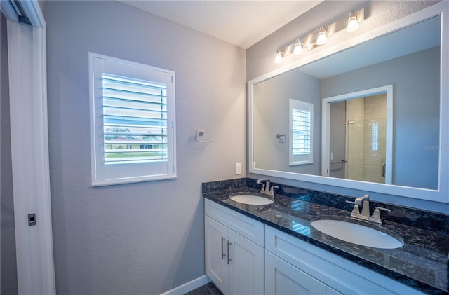 bathroom with a stall shower, a sink, and double vanity