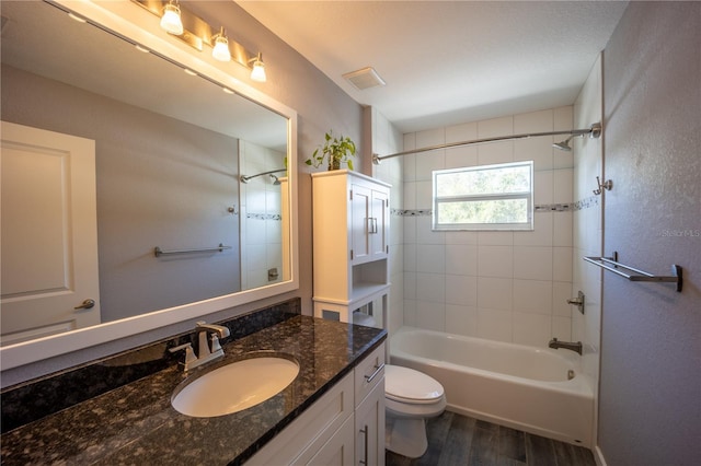 full bathroom with visible vents, toilet, wood finished floors, vanity, and washtub / shower combination