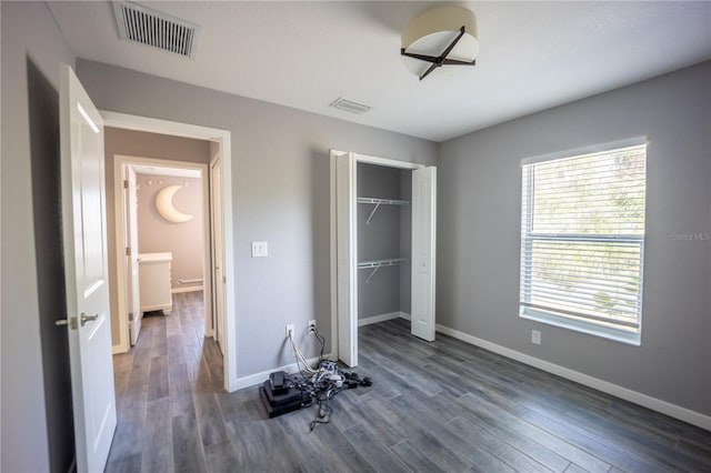 unfurnished bedroom with a closet, visible vents, baseboards, and wood finished floors