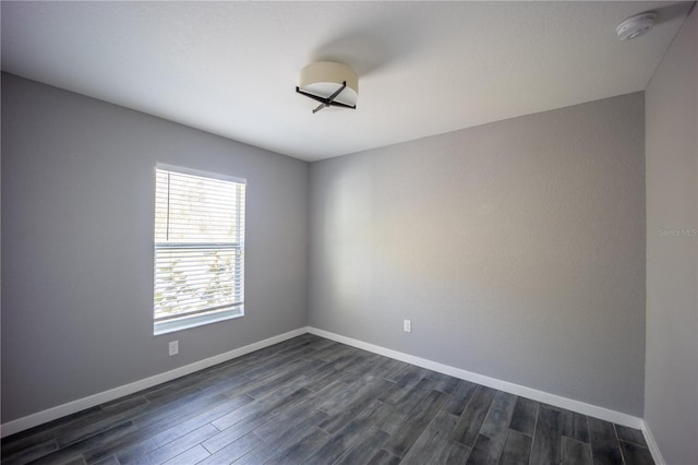 unfurnished room with baseboards and dark wood finished floors