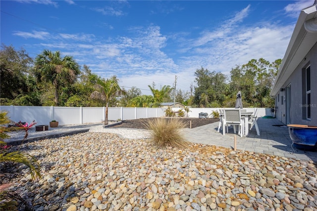 view of yard featuring a patio, outdoor dining area, and a fenced backyard