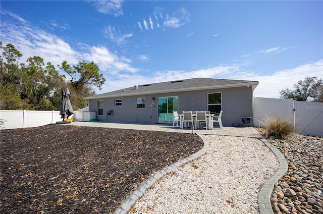 back of property with a fenced backyard, a gate, a patio, and stucco siding