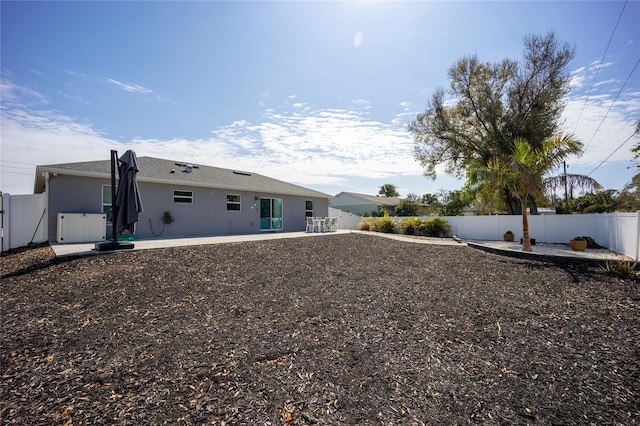 rear view of property featuring a patio, a fenced backyard, and stucco siding